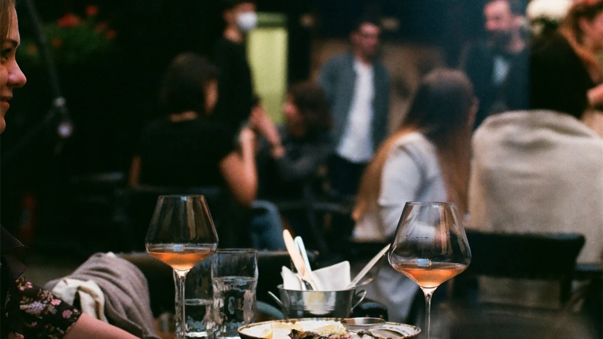 Grupo reunido em volta de uma mesa com taças de vinho
